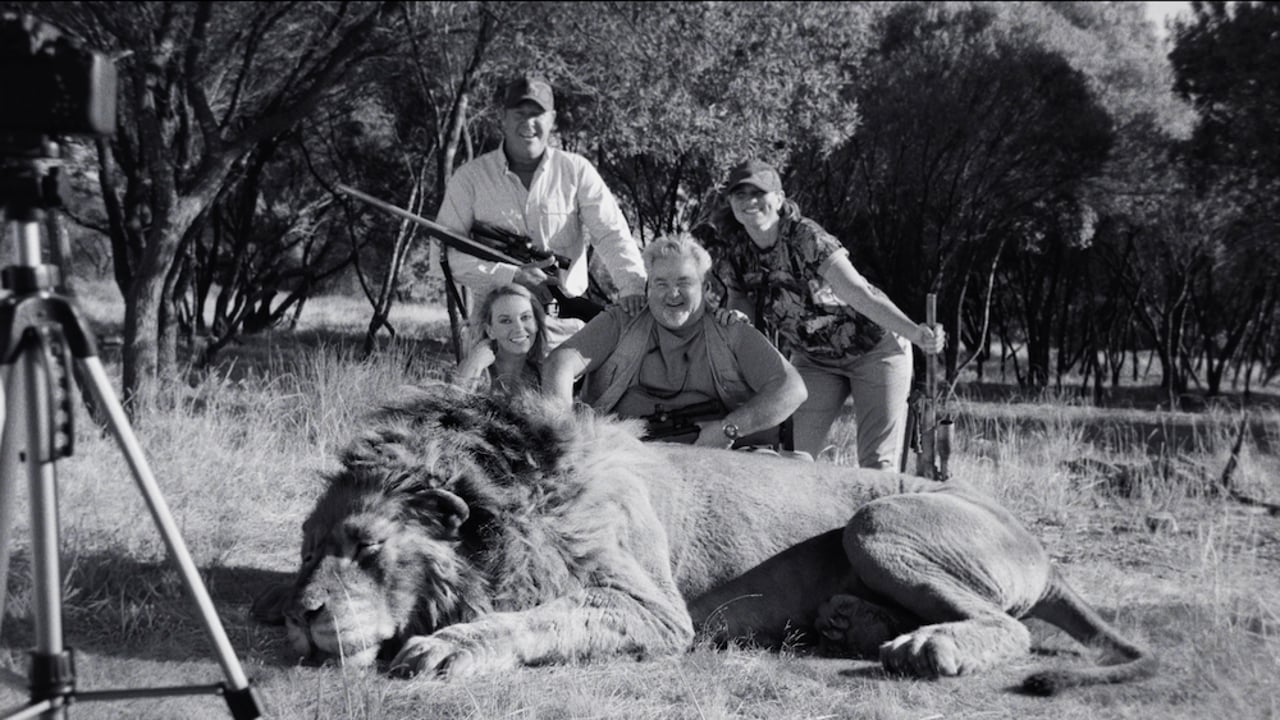 Hunting group posing with dead lion