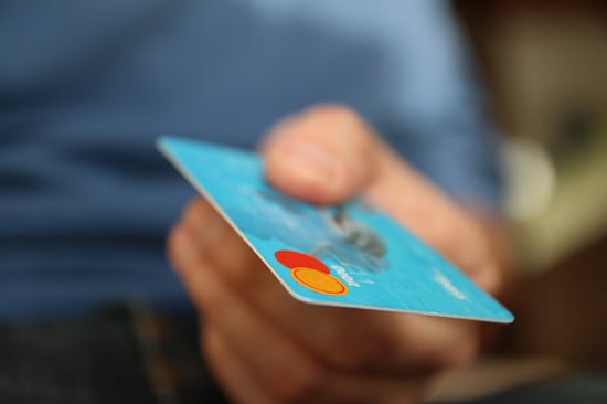 A light-blue credit card being held in someone's hand