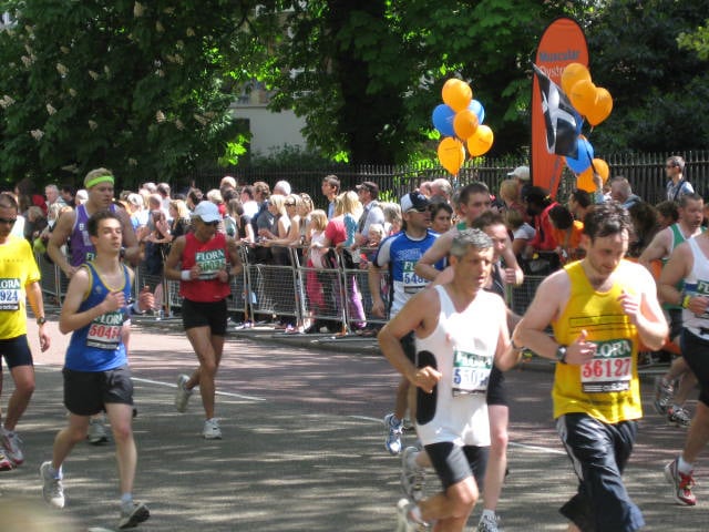 A group of people running at a race event. They are wearing running shirts that represent charities they are fundraising for.