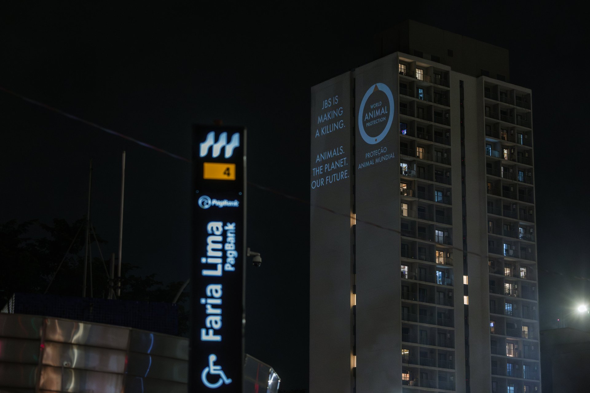A projection on the side of a tower block with World Animal Protection's logo on one side and reading "JBS is making a killing. Animals. The planet. Our future." on the other side