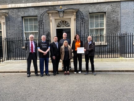 A group of people standing in front of no 10 Downing Street.