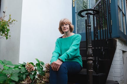 A senior woman in a turquoise jumper sitting on steps