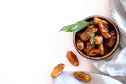 A bowl of dried dates on a white background