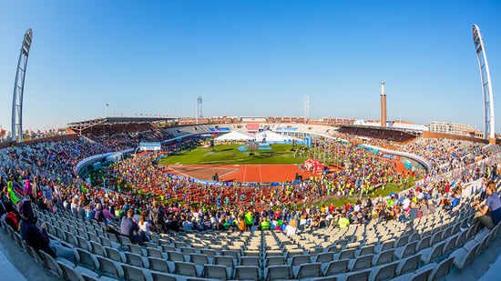 A panoramic view of a bustling stadium filled with spectators and participants, under a clear blue sky.