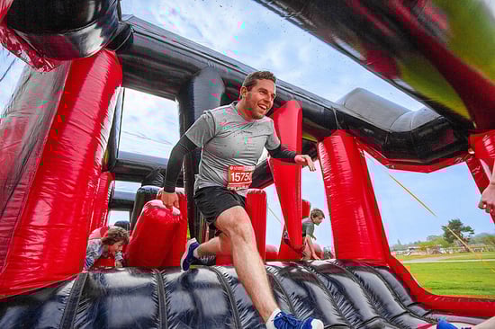 A runner is tackling an inflatable obstacle during a race.