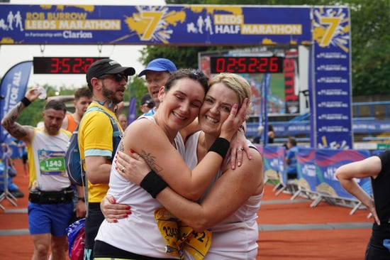 Two women hug each other at the marathon finish line.