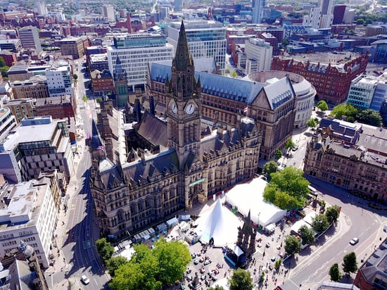 Aerial view of Manchester's tall town hall clock tower, surrounded by modern cityscape.