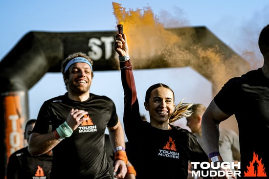 A Tough Mudder event featuring competitors running with the start sign in the background.