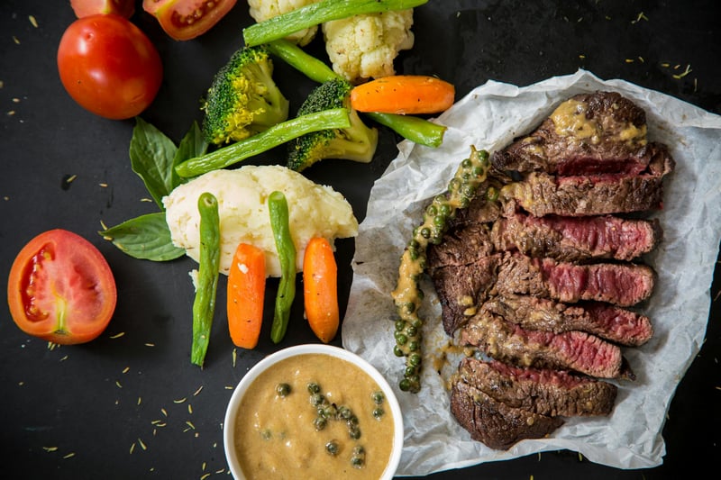 Medium rare steak surrounded by sauce and vegetables